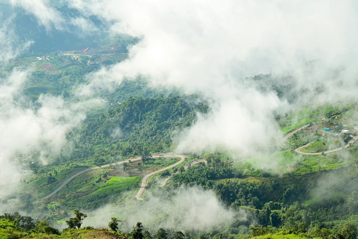 A mountain road winding through mist and cloud over the forested hills of Khao Kho in Phetchabun